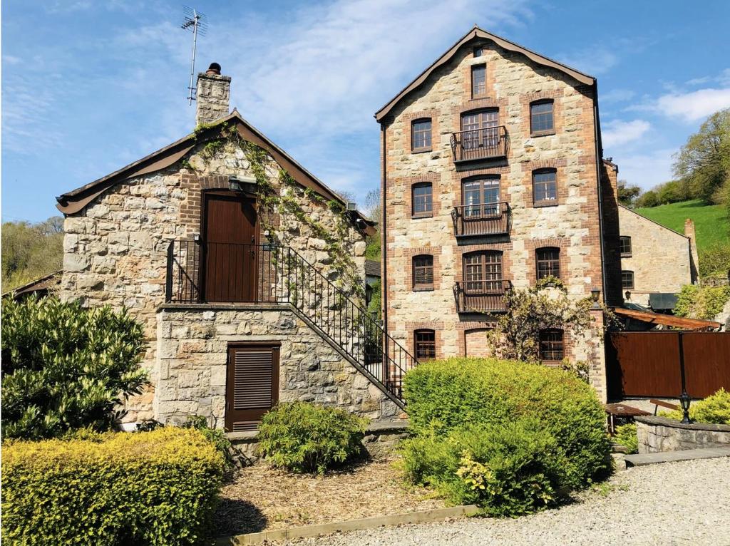 an old stone building with a balcony on it at The Old Mill Holiday Cottages, Nr Mold in Mold