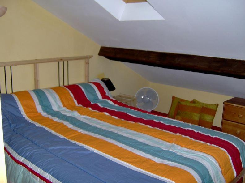 ein Bett mit einer bunten gestreiften Bettdecke in einem Schlafzimmer in der Unterkunft Gîte du petit Taïchou in Luzenac