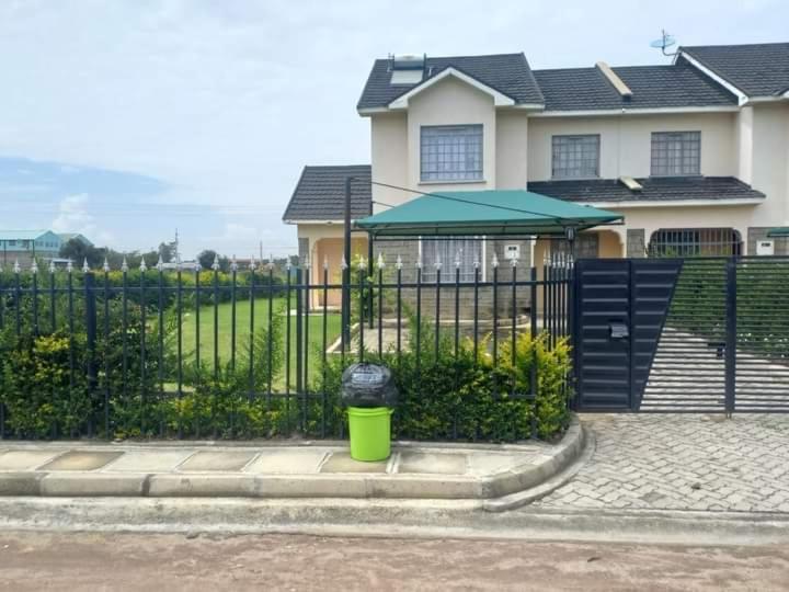 a green trash can in front of a fence at Vacay interprime villa #10 in Kitengela 