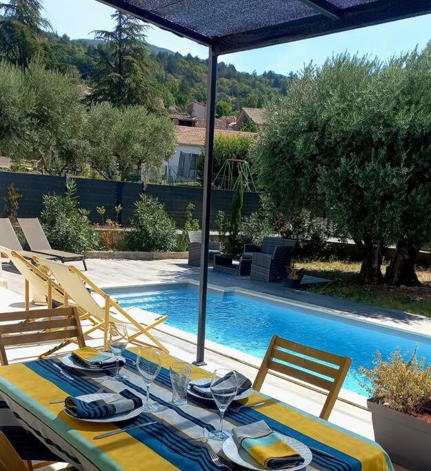 une table avec un chiffon de table bleu et jaune et une piscine dans l'établissement Villa Le Clos des Oliviers, à LʼEscale