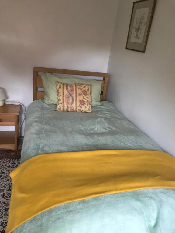 a bedroom with a bed with a yellow blanket on it at 18 Wixon Path in Buckinghamshire