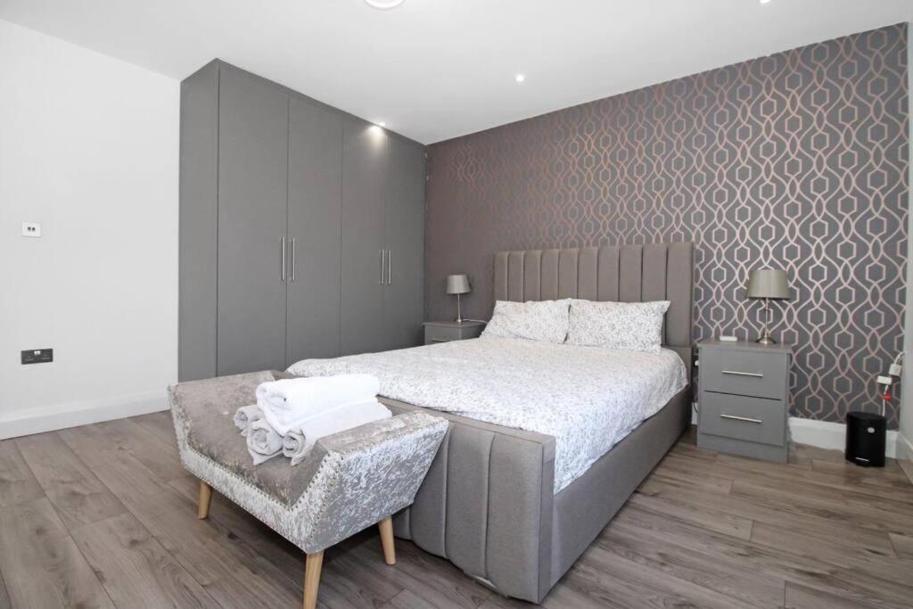 a bedroom with a large bed and a chair at Stunning 2 bedroom in Luton ! in Luton