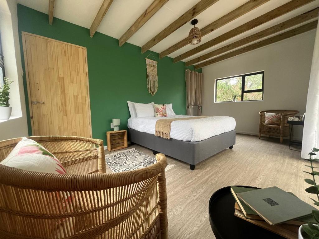 a bedroom with a bed and two wicker chairs at Forest Gate Estate in Plettenberg Bay