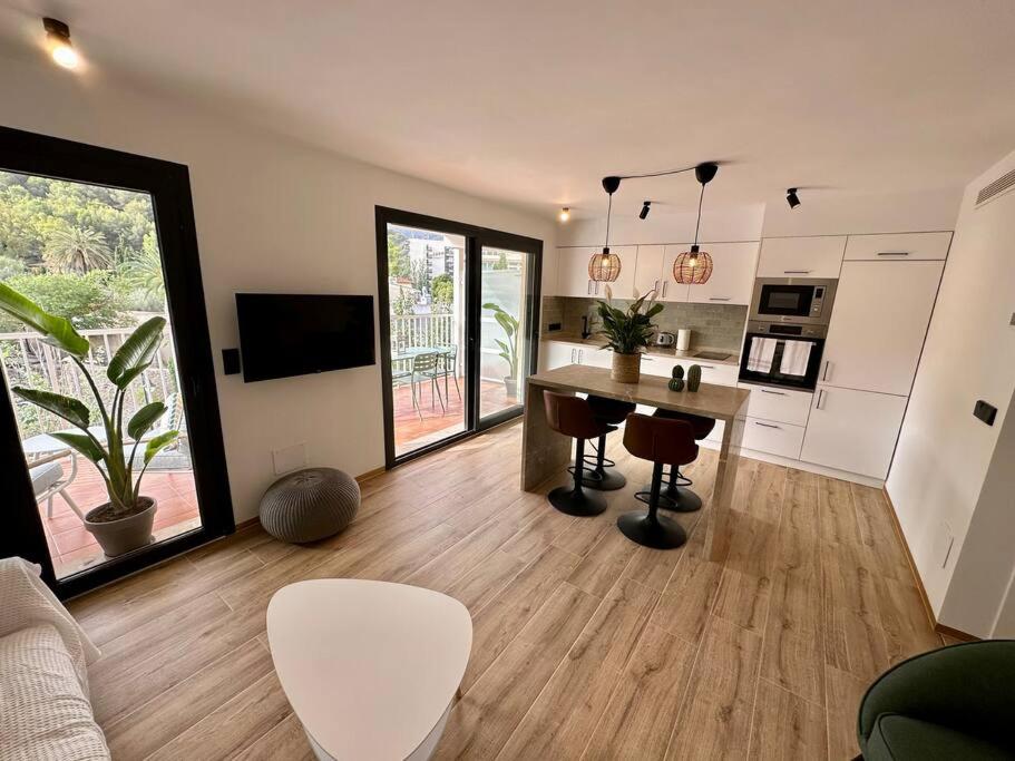 a living room with a table and a kitchen at Moderno y acogedor apartamento con terraza “ Llebeig” in Sóller