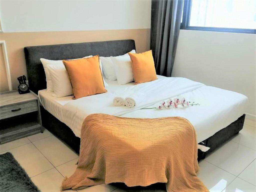 um quarto com uma cama com almofadas laranja e branca em Chambers PWTC By GrandRoyal em Kuala Lumpur
