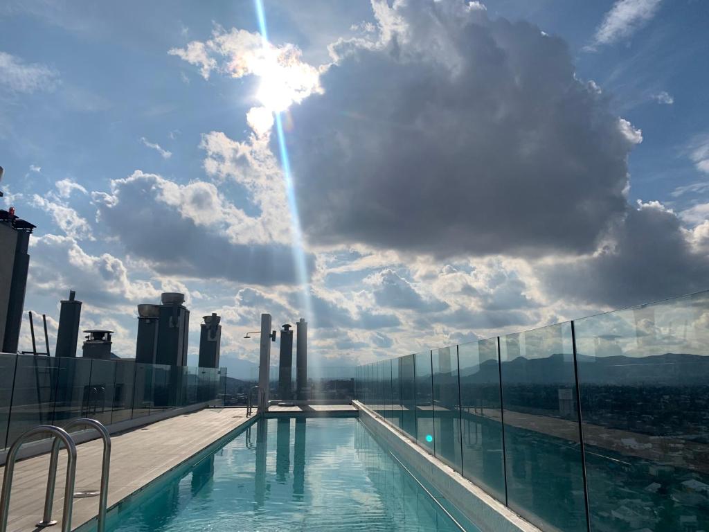 a swimming pool on top of a building with the sun shining at Depto/2p/Business Trip/Equipado. in Santiago
