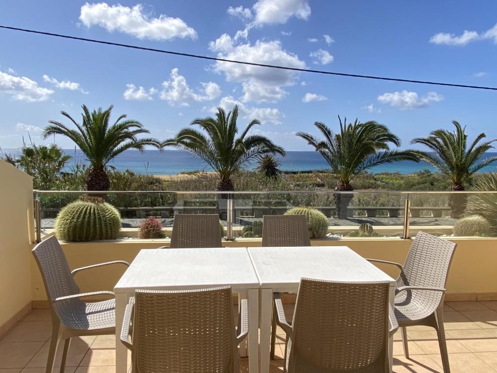 a white table and chairs on a balcony with palm trees at Casa das Pedras Pretas in Porto Santo