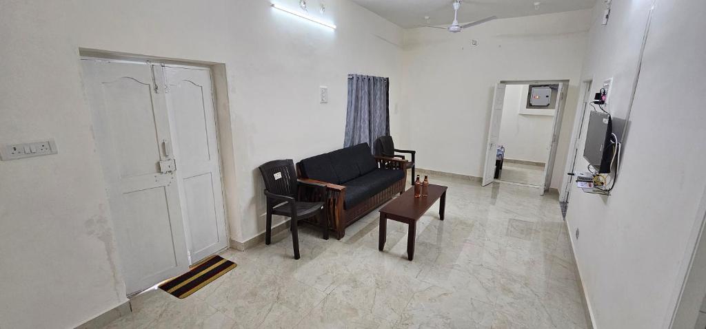 a living room with a black couch and a tv at SAIBALA HOMESTAY - AC 3 BHK NEAR AlRPORT in Chennai