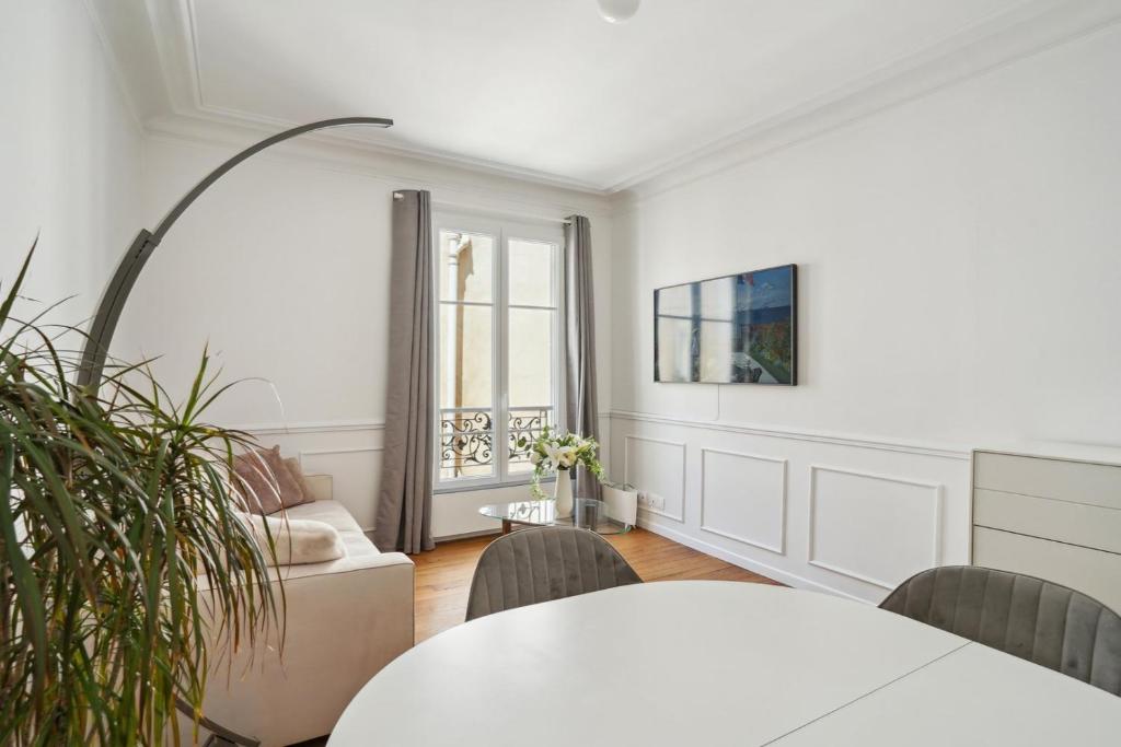 un salon blanc avec une table et des chaises dans l'établissement Le XVIe Chic - Paris, à Paris