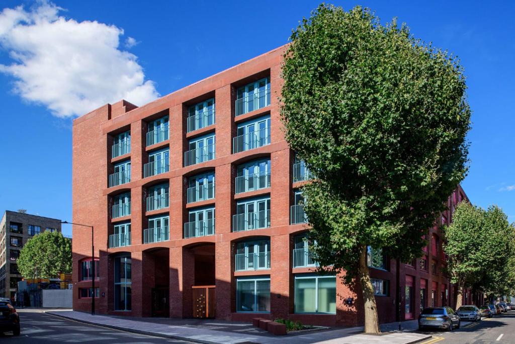 a red brick building with a tree in front of it at Cozy City Living Ensuites in trendy Wick Park Student Accommodation in London