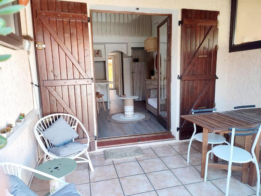 een patio met een houten deur en een tafel en stoelen bij Maison 10min à pied de la plage in Saint-Cyprien