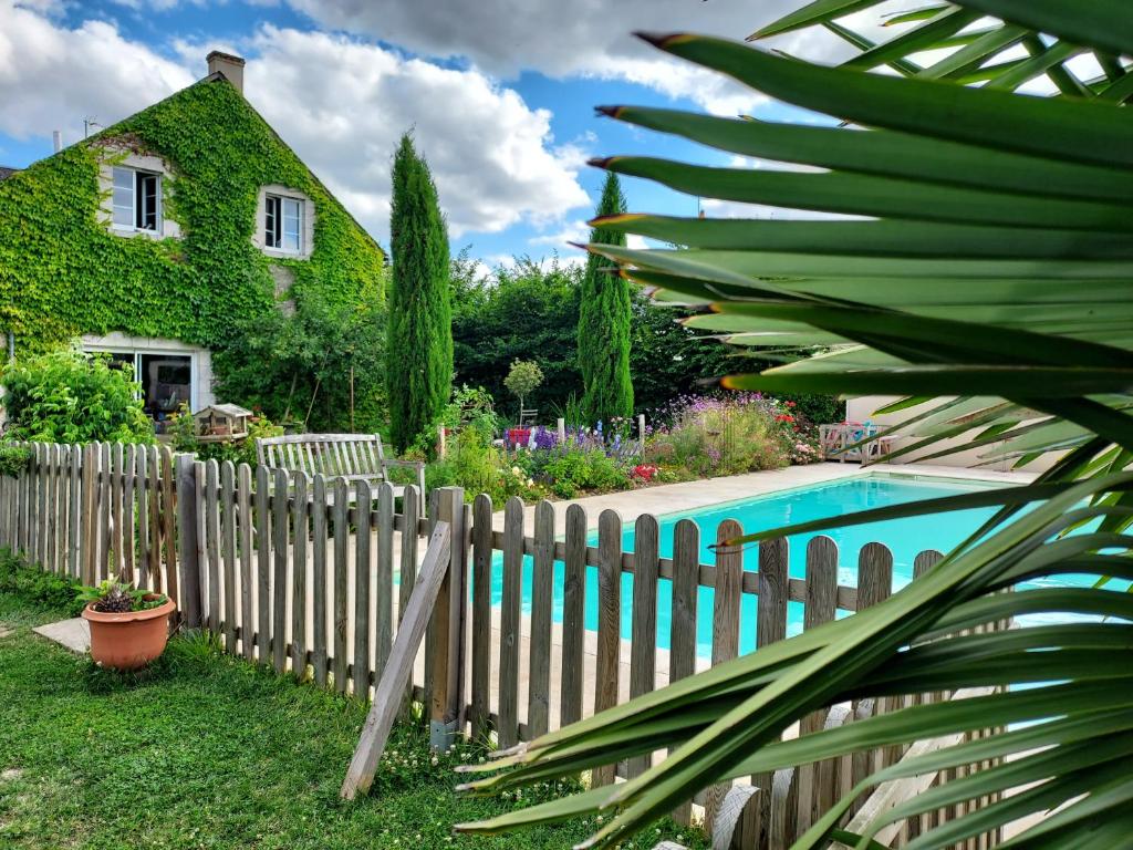 uma cerca em frente a uma casa com piscina em LE BONHEUR DES HÔTES em Suèvres