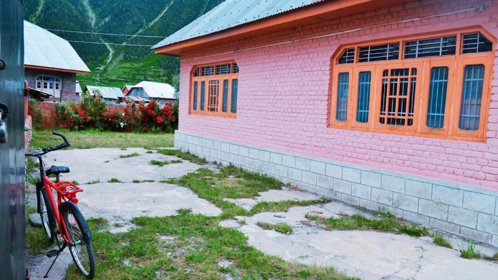 a red bike parked next to a pink building at Gurez Retreat in Kanzalwan