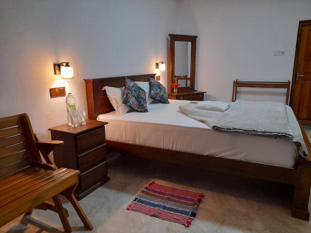 1 dormitorio con cama, silla y espejo en Amaya View Guest Inn en Haputale