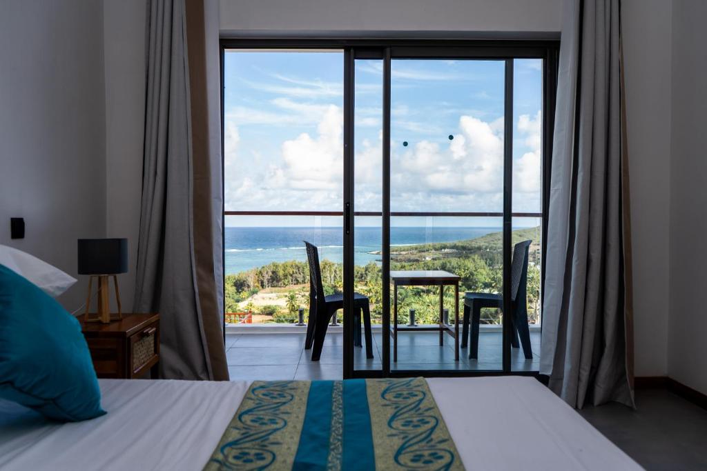 a bedroom with a bed and a view of the ocean at Le Marin, Rodrigues Island in Rodrigues Island