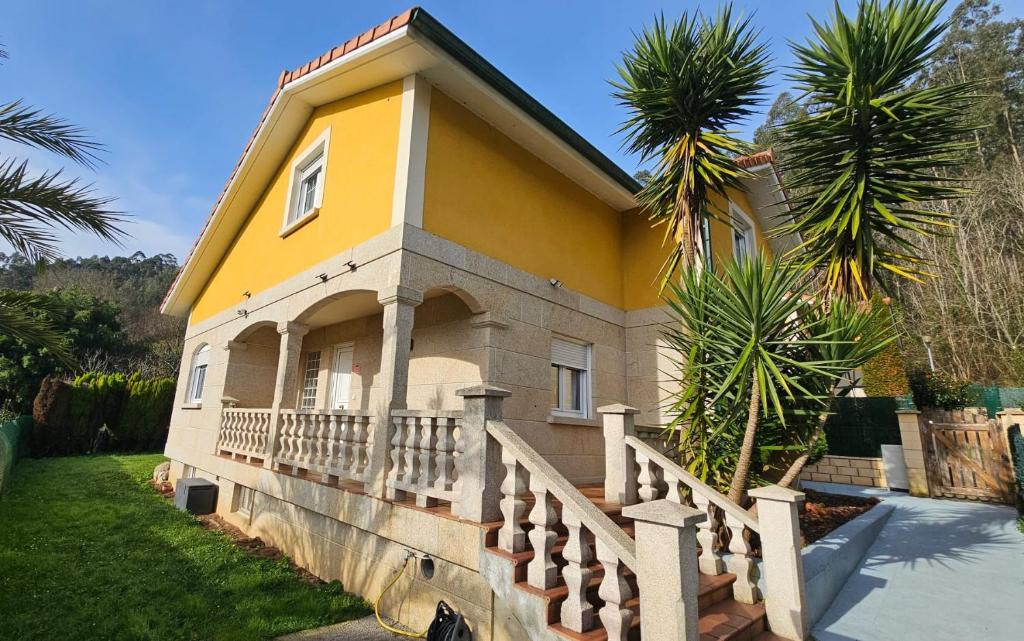 a yellow house with a porch and a palm tree at Viento Del Norte in Pomar