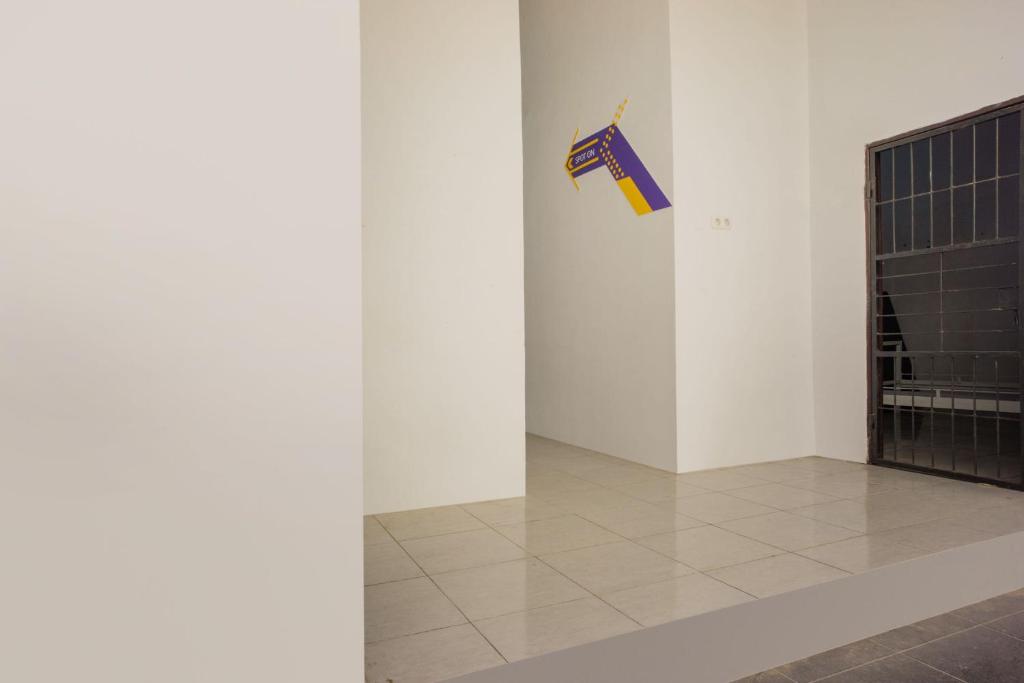um quarto branco com uma bandeira pendurada numa parede em OYO 93304 Wisma La Oda Syariah em Pangkajene