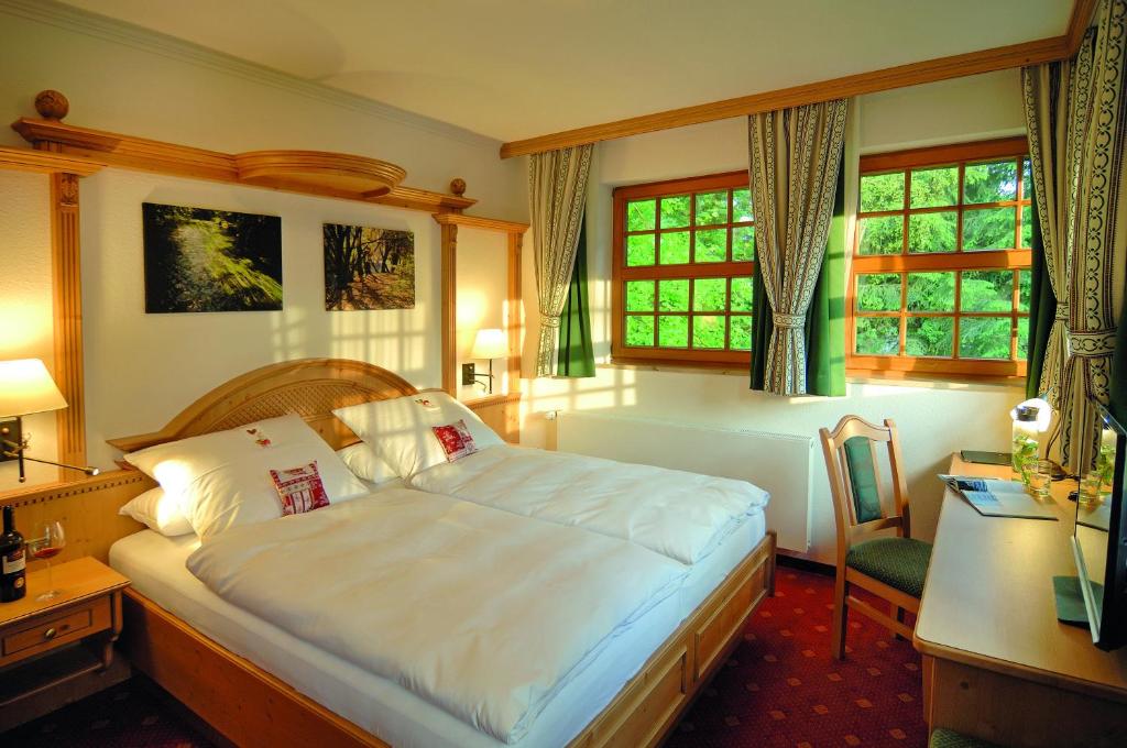 a bedroom with a bed and a desk and windows at Alpenhof in Gauting