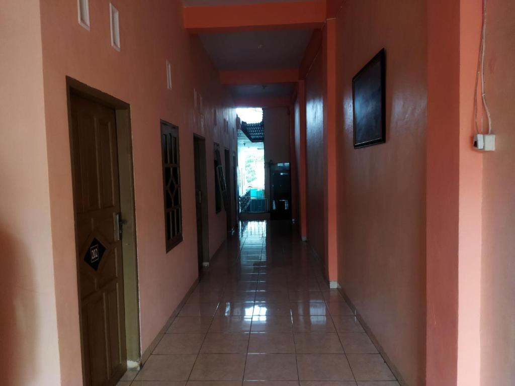 un couloir vide avec des murs orange et du carrelage. dans l'établissement OYO 93306 Penginapan Permata Hijau Syariah, à Parepare