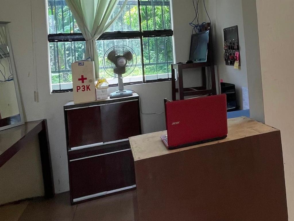 un escritorio con un portátil rojo encima en OYO 93178 Al Bait Homestay. en Lhokseumawe