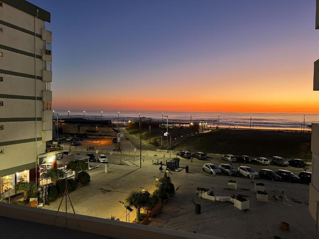 vista para um parque de estacionamento e para a praia ao pôr-do-sol em Casa Costa em Costa da Caparica