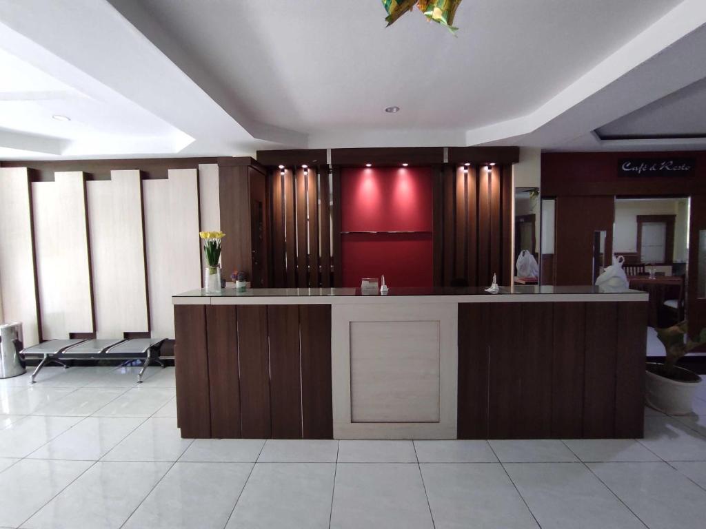 un vestíbulo con un mostrador y una pared roja en OYO 93278 Wisma Syariah Lahundape, en Kendari