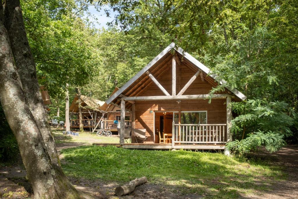 une cabane en rondins dans les bois avec une terrasse couverte dans l'établissement Huttopia Versailles, à Versailles