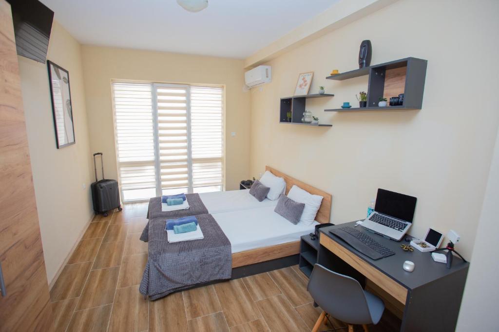 een kleine kamer met een bed en een bureau met een computer bij Veliko Turnovo Studios - Stylish & Convenient in Veliko Tŭrnovo