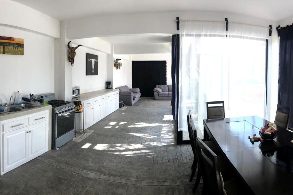 a kitchen with white cabinets and a table and a living room at Quinta del Eden, 9PX, Pool, BBQ, Pet Friendly in Matehuala