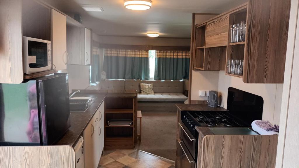 a small kitchen with a stove and a couch at 6 dunster court haven park doniford bay in Watchet