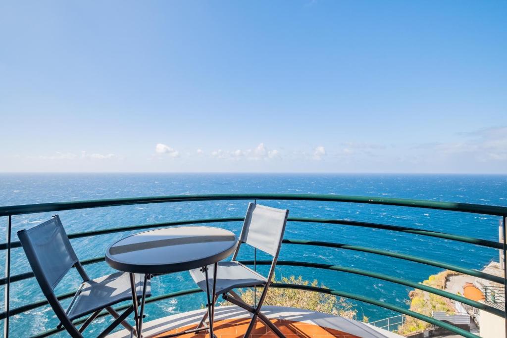 a balcony with chairs and a table and the ocean at Sea View in Câmara de Lobos