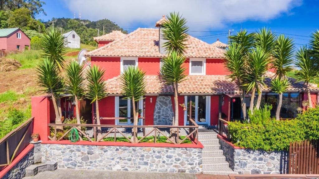 una casa rossa con palme di fronte di São Jorge Cottage a Santana