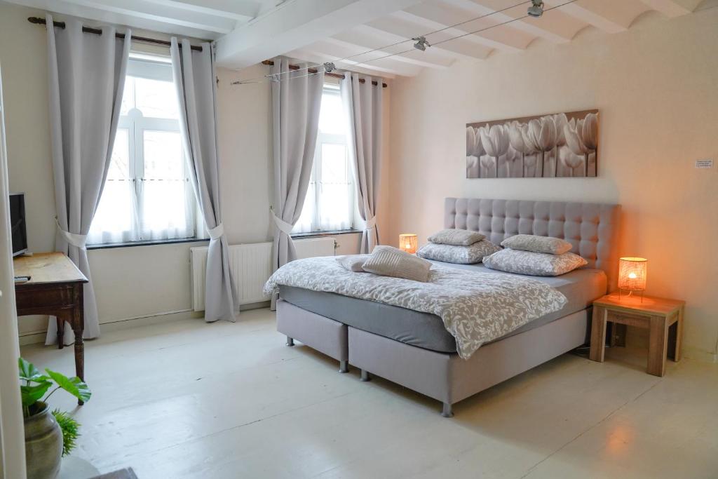 een slaapkamer met een bed met 2 lampen en 2 ramen bij Gastenkamers In de Bleick in Rekem