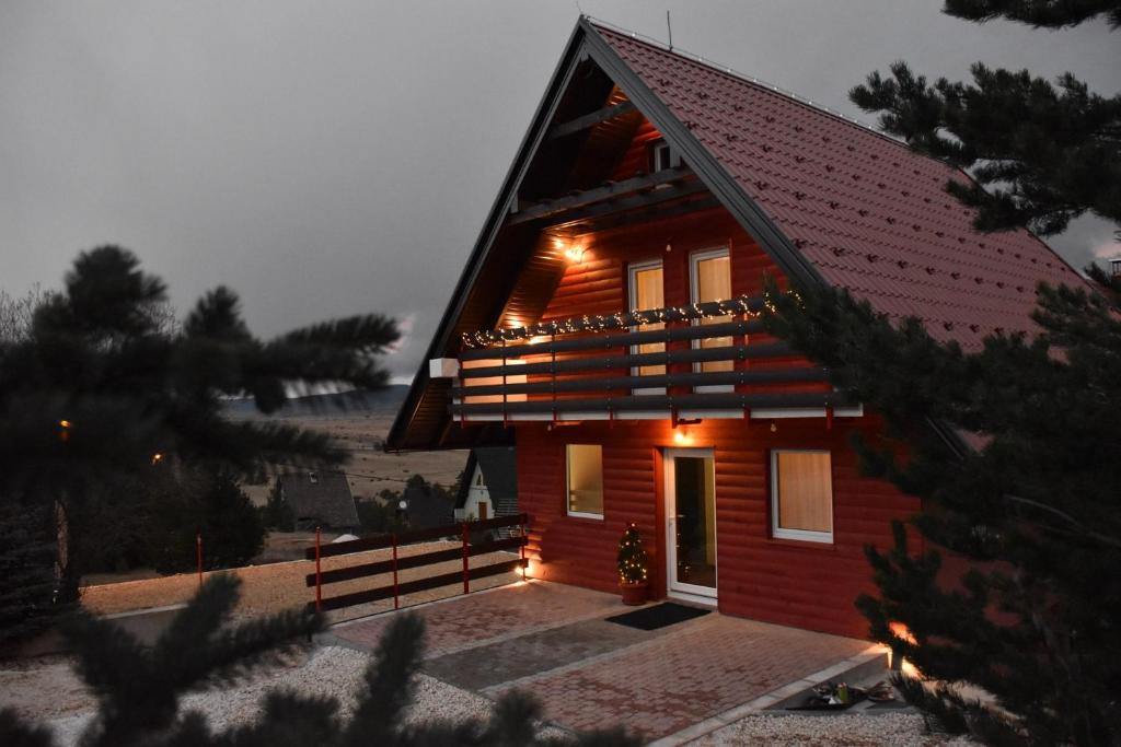 a red house with lights on the side of it at Villa Šola in Kupres
