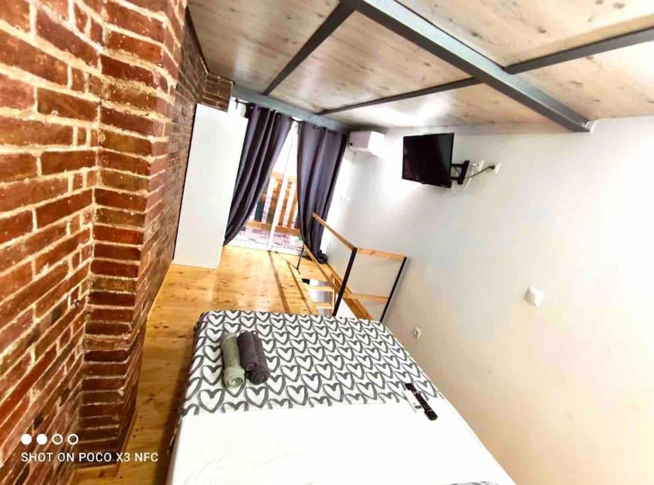 Ce lit se trouve dans une chambre dotée d'un mur en briques. dans l'établissement 1 Apartamento duplex con terraza y balcon a 2 calles del metro B8, à Barcelone