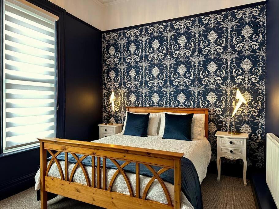 a bedroom with a bed and a black and white wallpaper at Birkdale Retreat in Southport