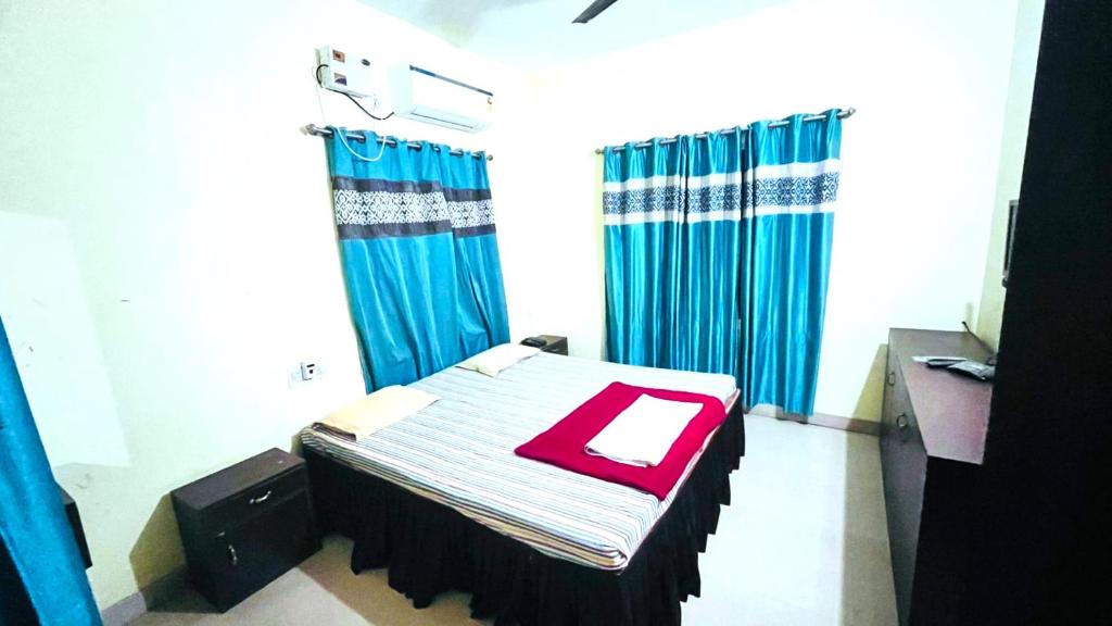 Habitación pequeña con cama y cortinas azules en Goroomgo New Sriyansh Puri, en Puri