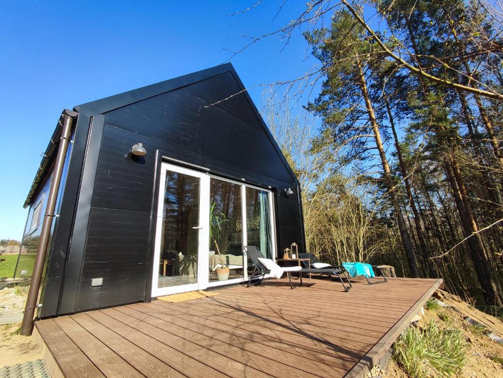 Casa cubierta de color negro con terraza de madera en Modern Sauna Cabin in Horse Ranch, en Lieplaukė