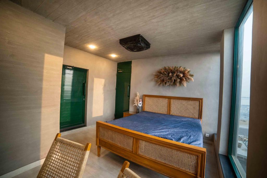 a bedroom with a bed and two chairs and a window at Blpl Cabane A luxury beach house in Karachi