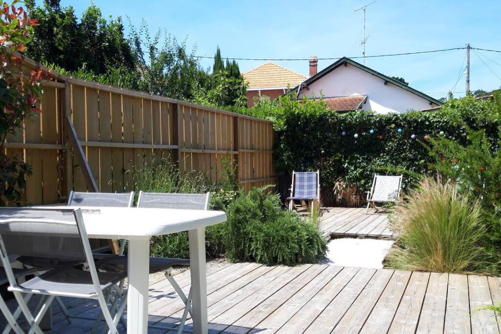 une terrasse en bois avec une table et des chaises. dans l'établissement Agréable maison à Arcachon, à Arcachon