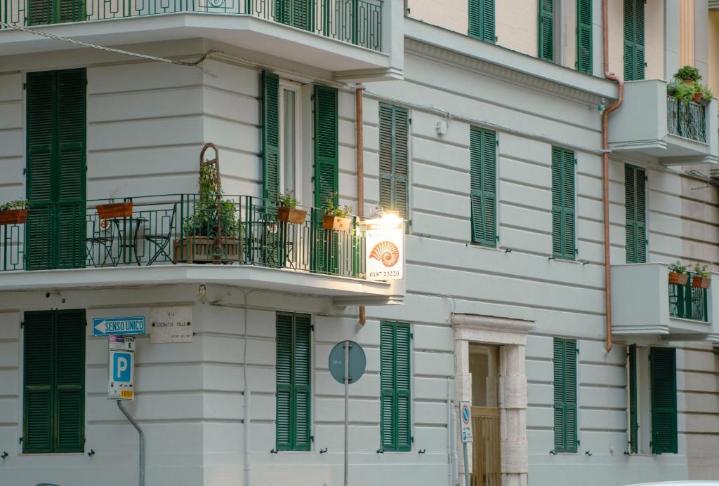 a white building with green shutters and a balcony at Nautilus Hotel in La Spezia