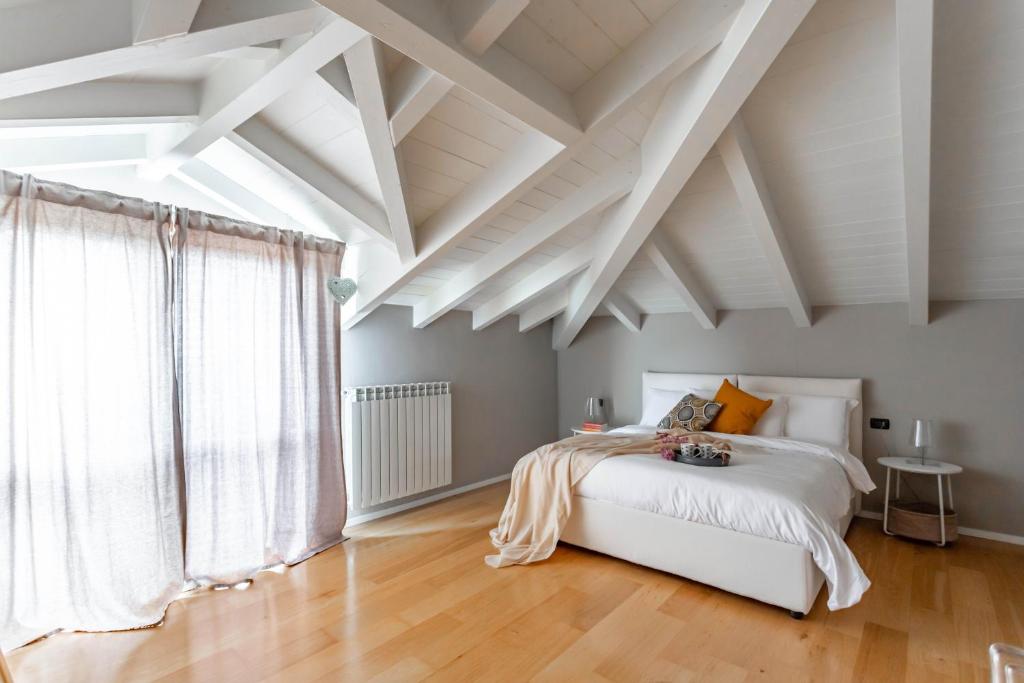 1 dormitorio con techo blanco, 1 cama y ventana en Mansarda Tra Le Risaie - Certosa di Pavia - by Host4U, en Torre del Mangano