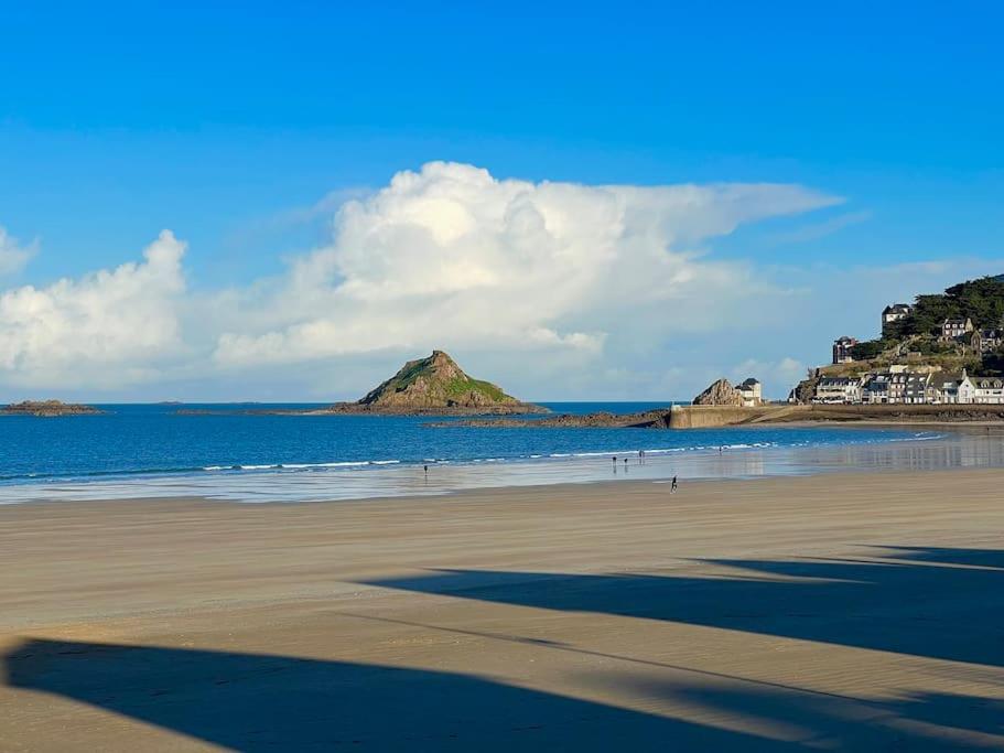 une plage avec une colline au loin et l'océan dans l'établissement Appartement à deux pas de la mer, à Pléneuf-Val-André