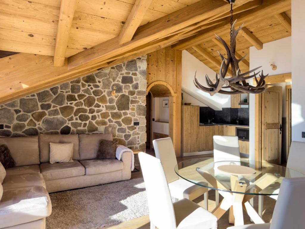 un soggiorno con tavolo in vetro e parete in pietra di Silva: The Alpine Chalet a Livigno