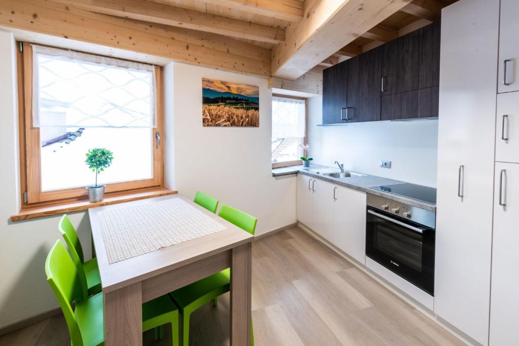 een keuken met een houten tafel en groene stoelen bij Appartamento vacanze Piazza in Fondo