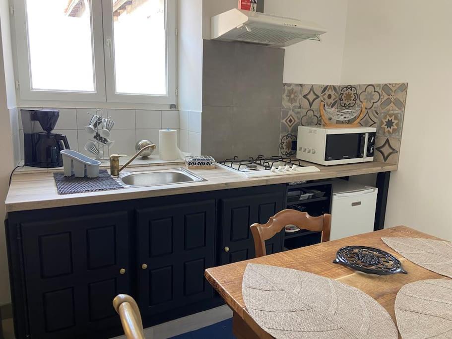een keuken met een wastafel, een tafel en een magnetron bij Joli loft rénové in Payré