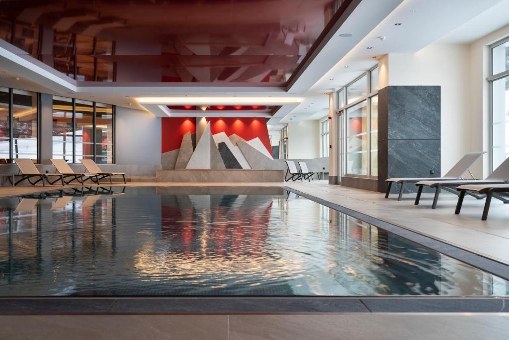 a pool in a building with chairs and a fountain at Hôtel Alhena in Flaine