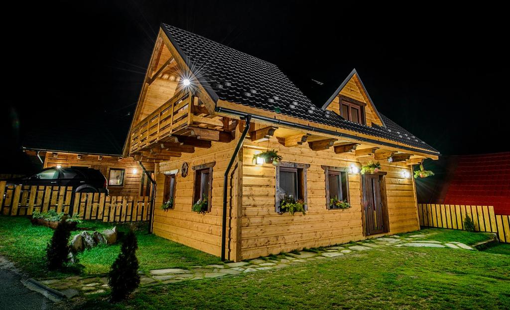 una pequeña casa de madera con luces encendidas por la noche en Chaty Ski Telgárt, en Telgárt