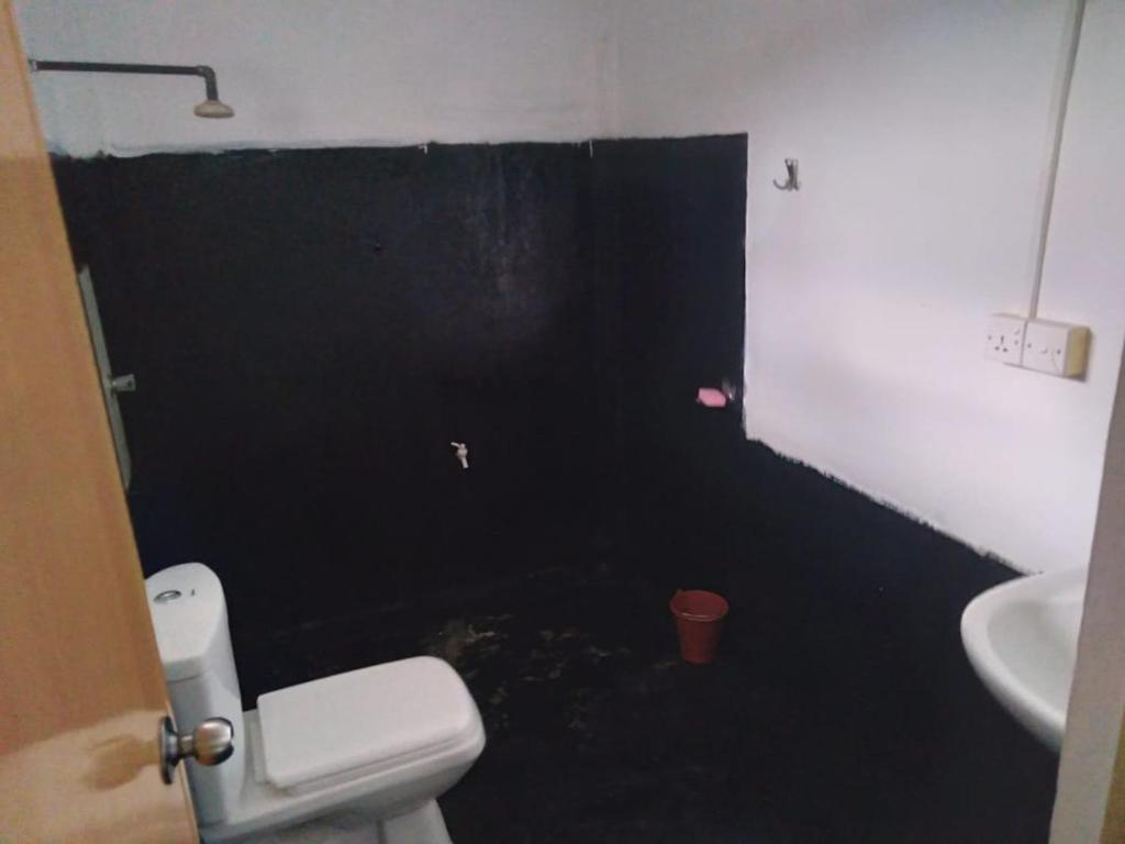 La salle de bains est pourvue d'un mur noir, de toilettes et d'un lavabo. dans l'établissement SENN Homestay, à Polonnâruvâ