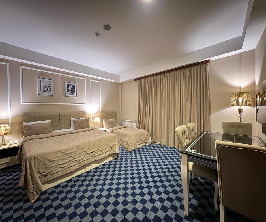 a hotel room with two beds and a desk at Sea Pearl Hotel in Baku